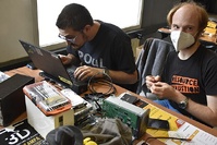Hackers working on Linux laptop with computer disks and repair kits - Milano 2022